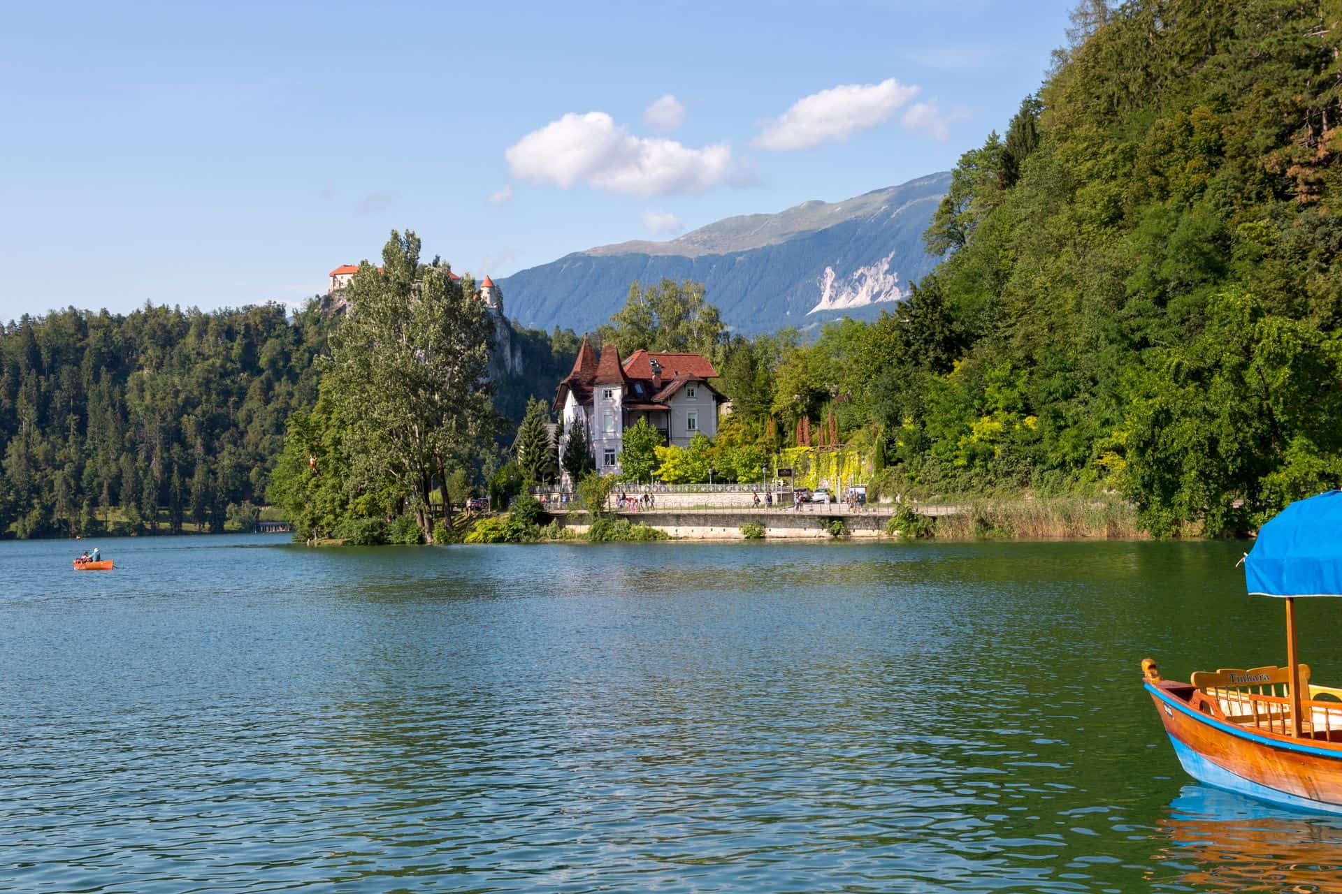 Pletna boat crossing Lake Bled with Bled Castle and the island church visible among the trees, Slovenia