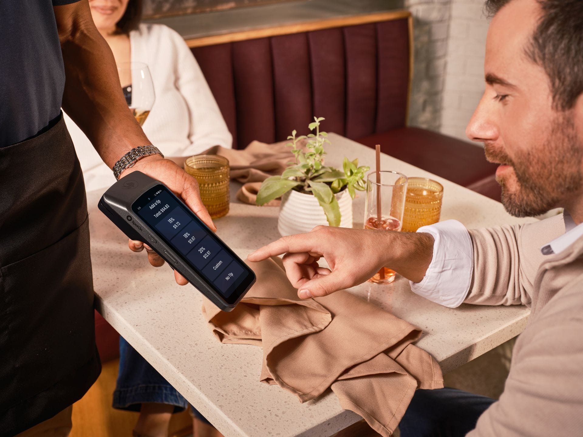Diner adding a tip on a handheld card payment terminal in a restaurant